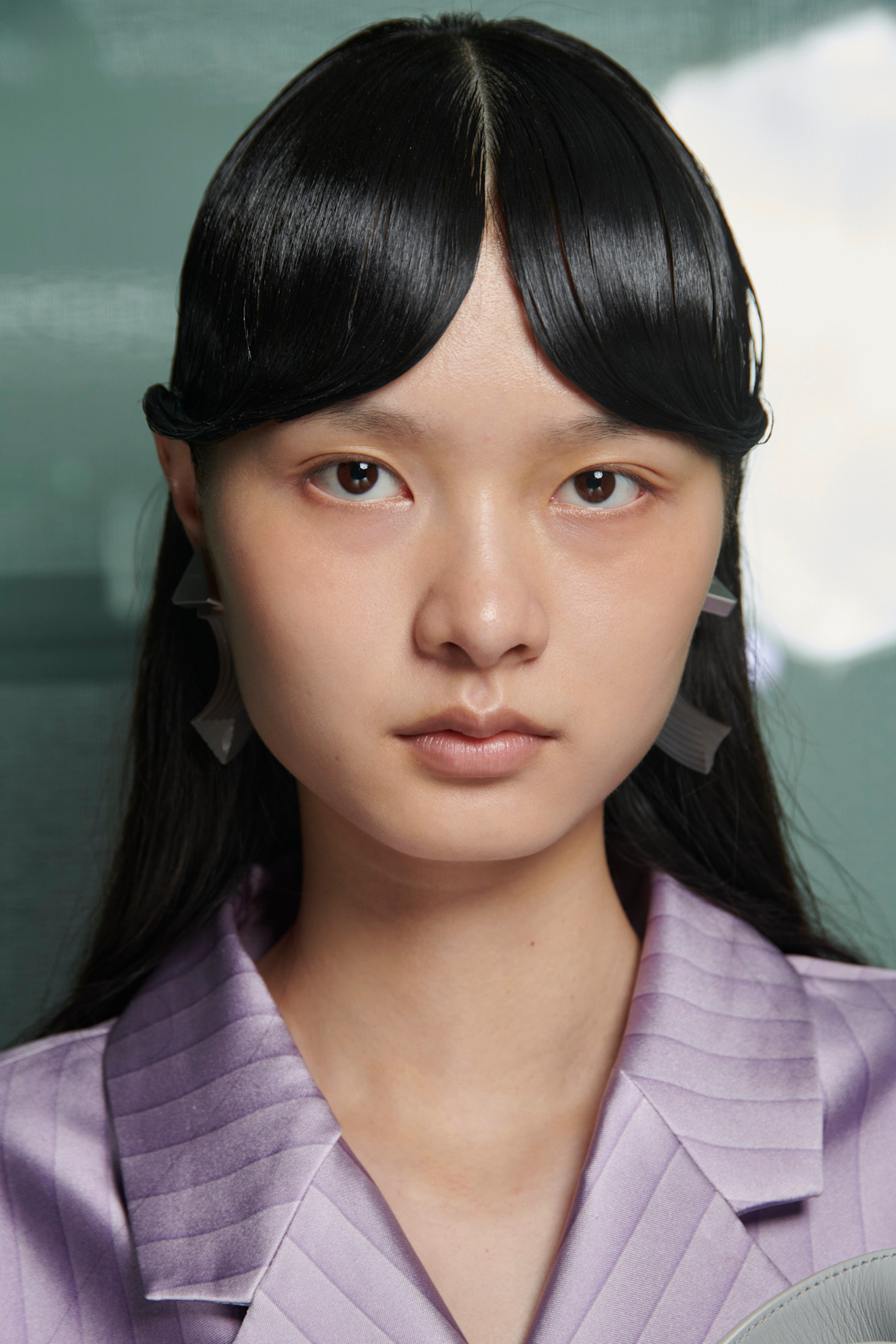 Defined curtain bangs in the middle on a model with clear skin and a purple top