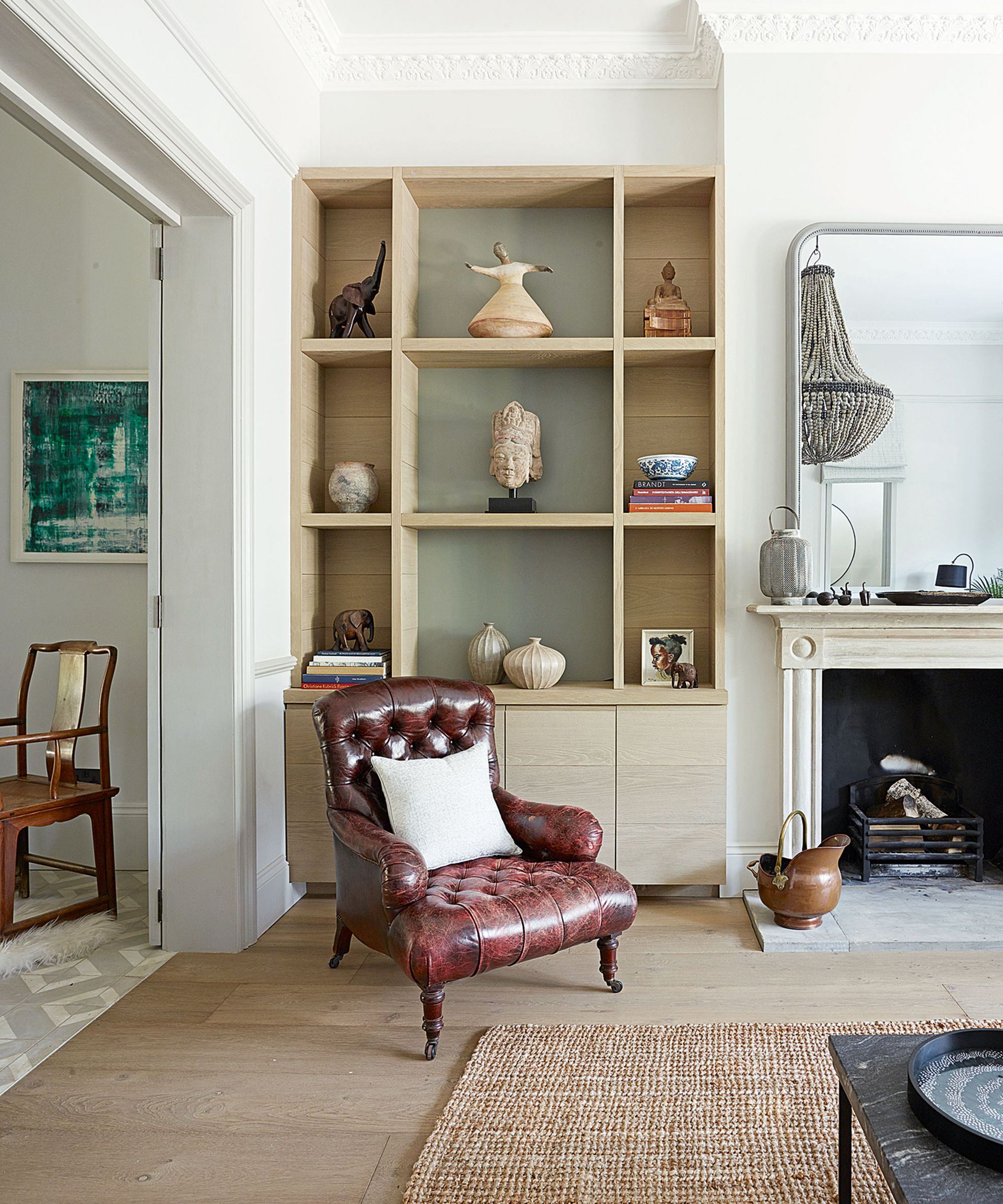 A brown leather chesterfield armchair in front of a wooden shelf unit