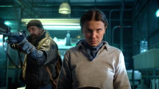 L-R: Hopper (David Harbour) holds a gun next to Eleven (Millie Bobby Brown) in a scene from "Stranger Things" season 5