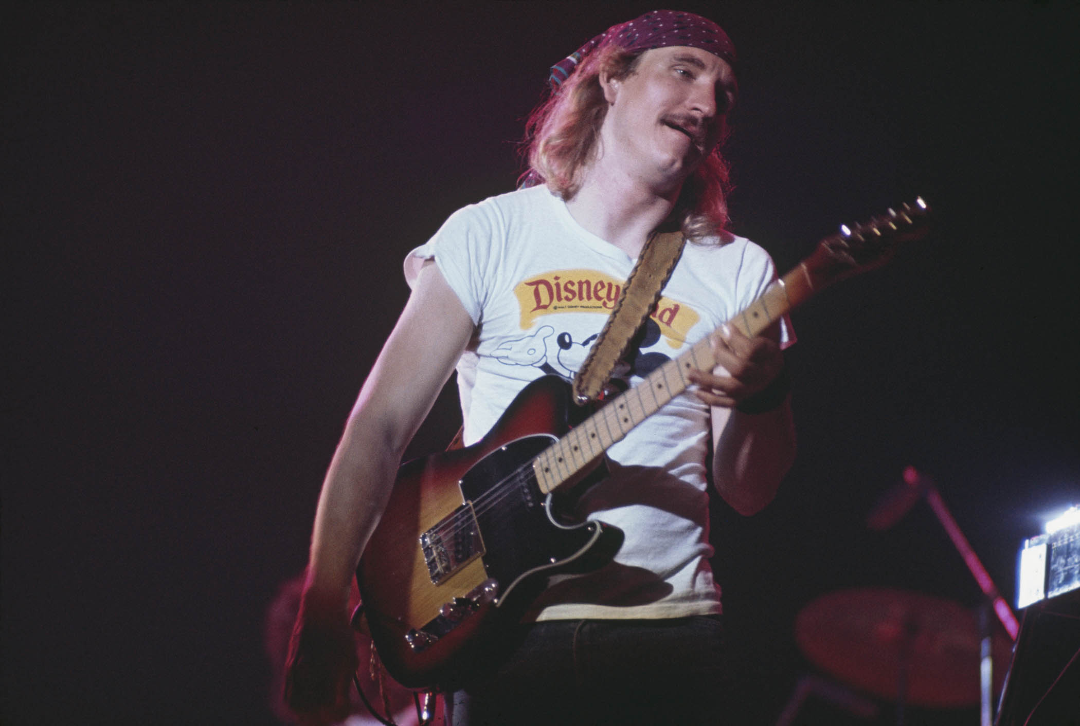 Joe Walsh wears a Disneyland T-shirt and plays a Telecaster live onstage in 1977.