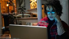 A woman looks focused as she looks at her laptop in her living room.