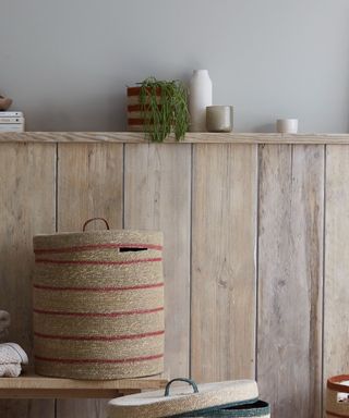 An entryway with a wooden wall and a woven storage basket with a lid