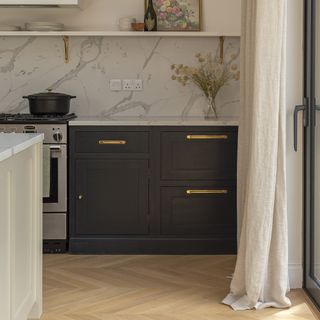 Black shaker kitchen with marble backsplash and long cream curtains against french doors.