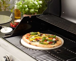 BBQ with a pizza cooking on a pizza stone