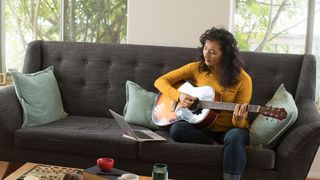 Young woman playing her guitar at home
