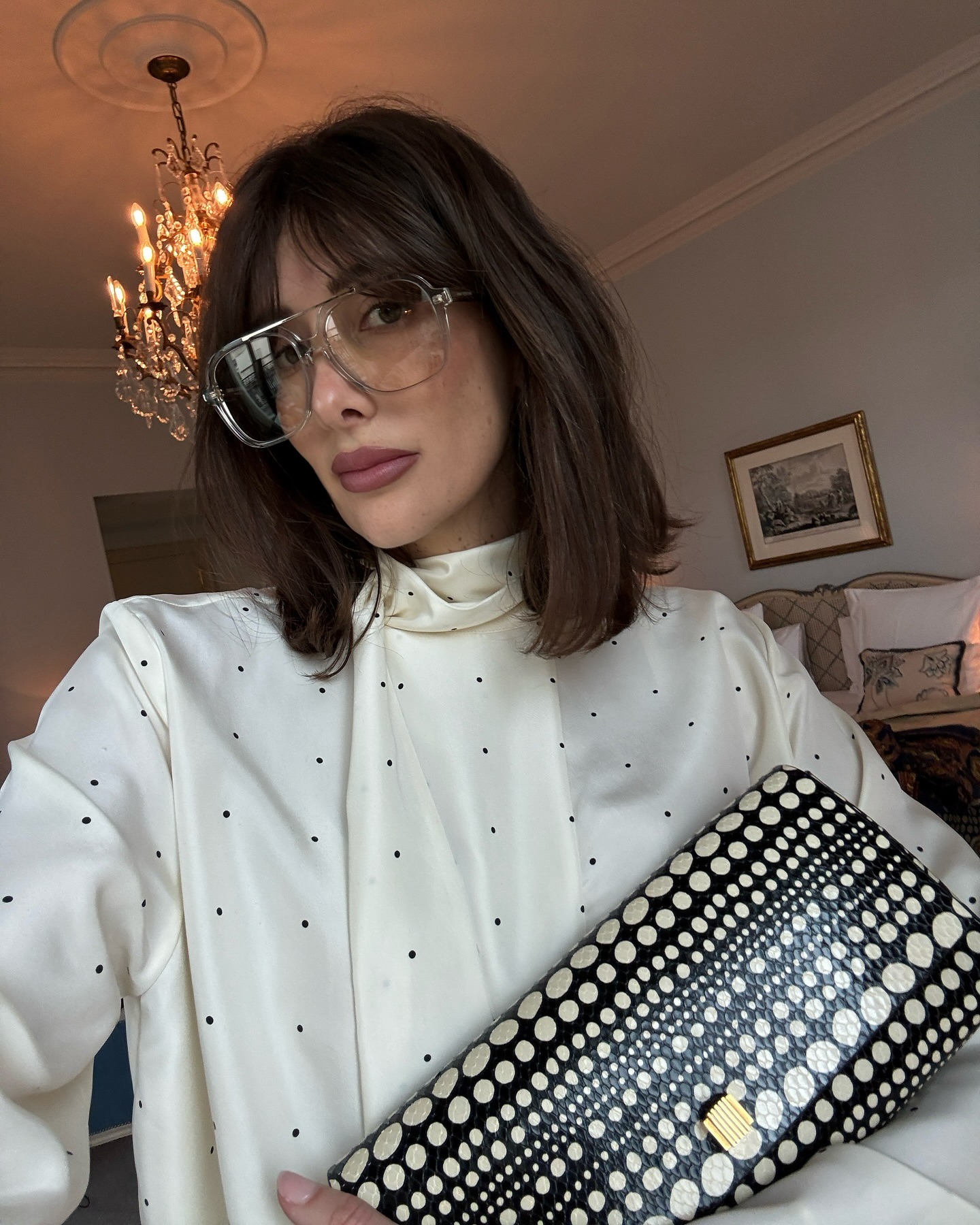 A woman taking a selfie wearing oversized glasses with a long, serrated bob and fringe