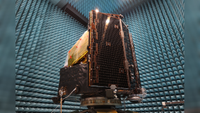 Bronze shiny spacecraft electronics in a room with blue padding on the walls. 