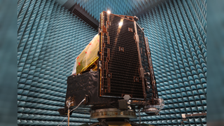 Bronze shiny spacecraft electronics in a room with blue padding on the walls. 