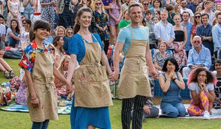 Great British Baking Show Steph, Alice, and David holding hands in front of the finale crowd