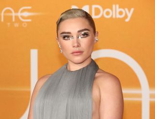 Florence Pugh wearing a grey gown with a silver eye look and diamond earrings