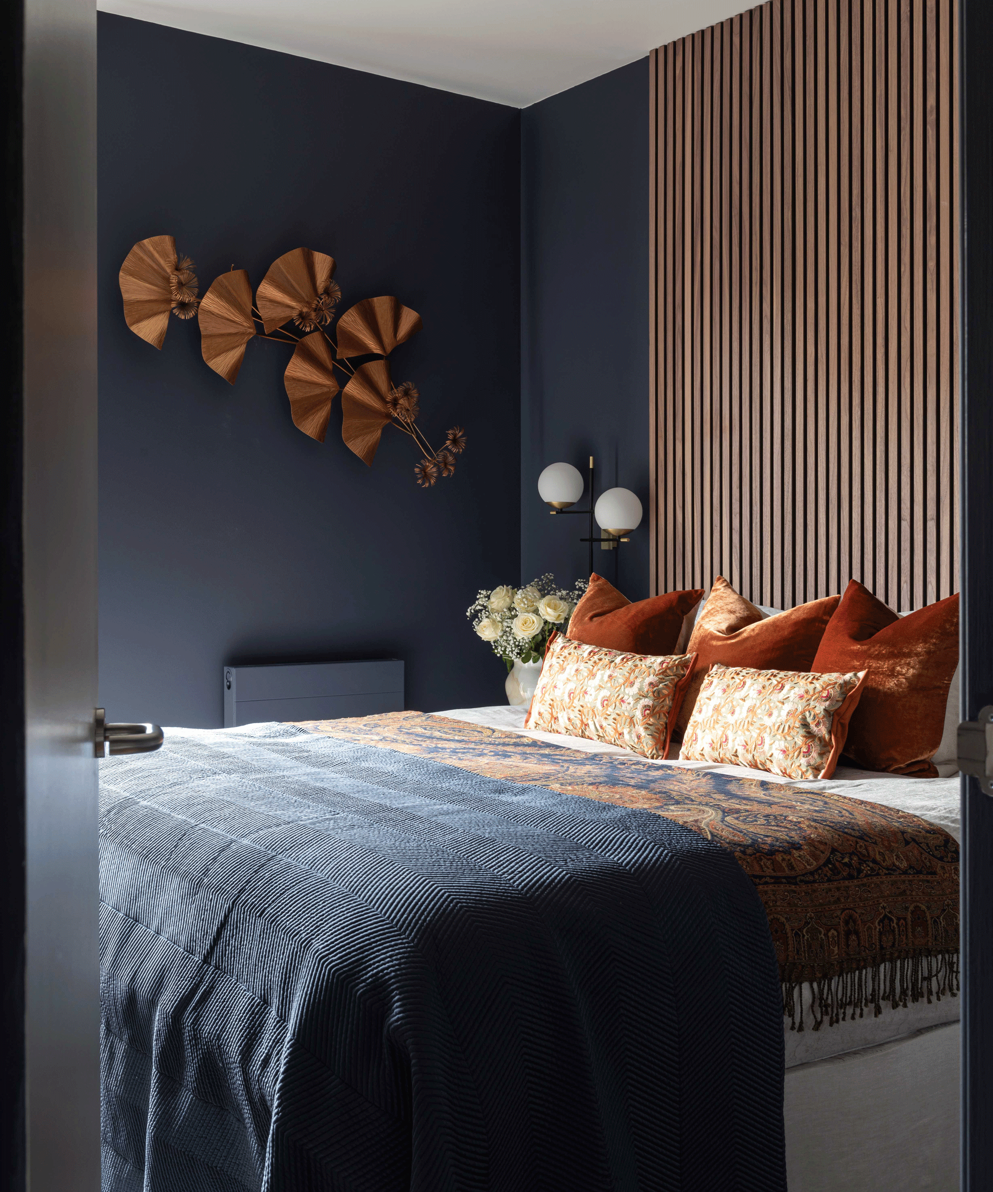 Navy bedroom with burnt orange soft furnishing