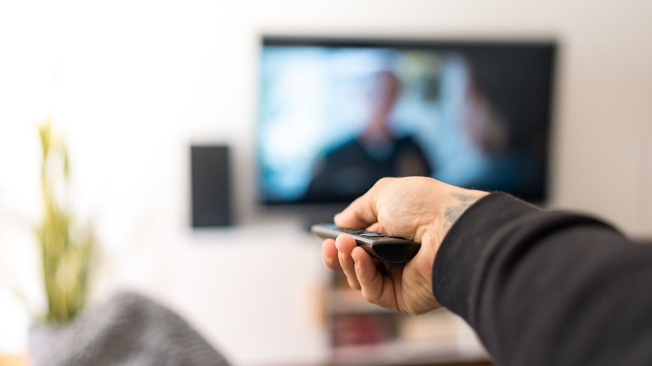 Arm with remote control pointed at TV.