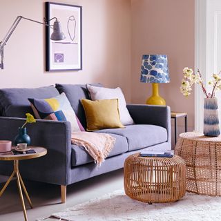 Living room with pale pink walls and grey sofa and yellow and blue accents
