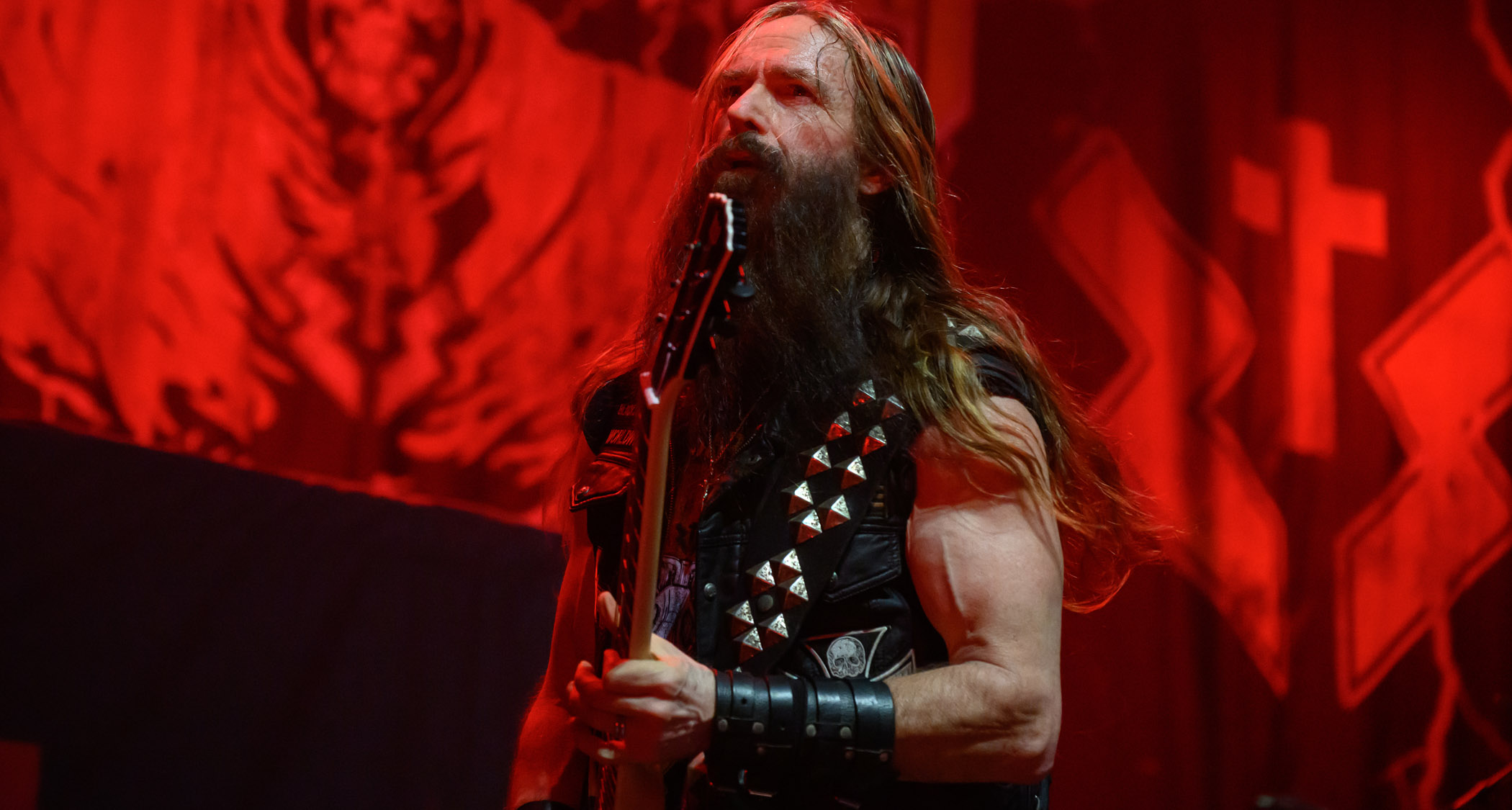 Zakk Wylde performs with Black Label Society on a stage bathed in red lights.