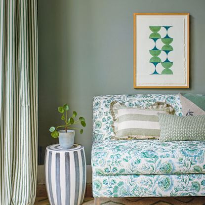 Green living room with botanical print sofa and geometric artwork