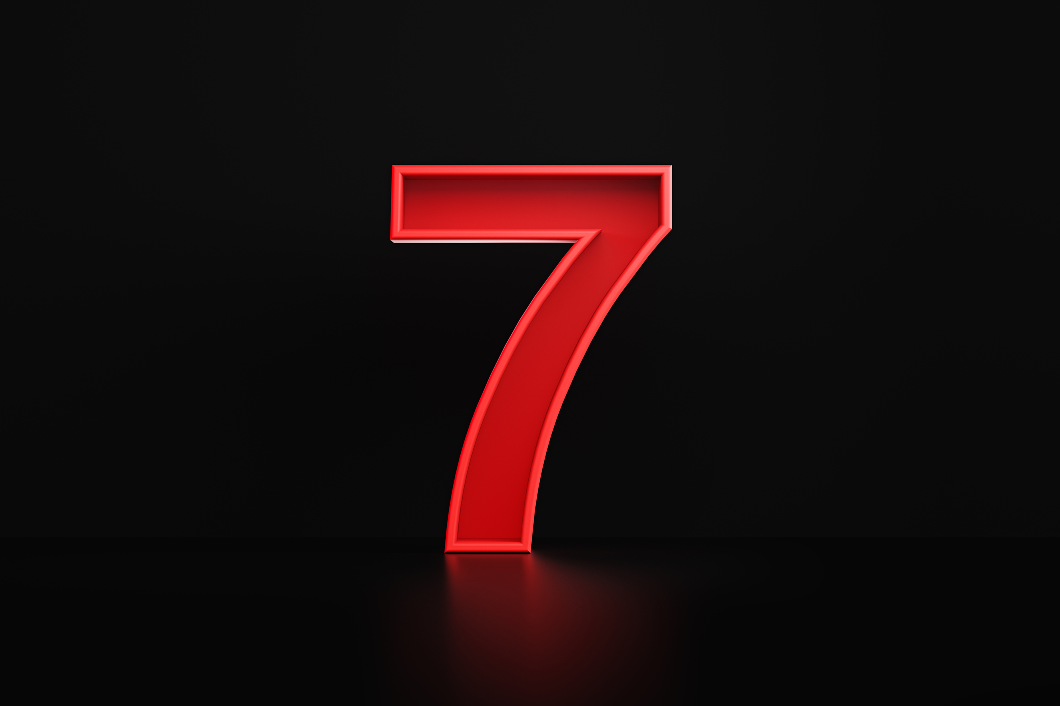 Red number seven sitting on a black background. 