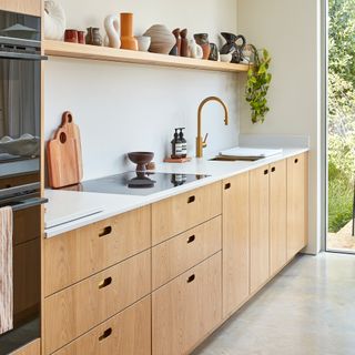 a row of wooden kitchen base cabinets with open shelving above