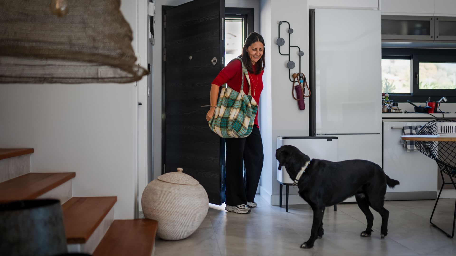 woman arriving home without immediately greeting black labrador