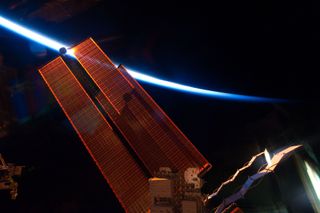 Intersecting the thin line of Earth's atmosphere, International Space Station solar array wings are featured in this image photographed by an STS-134 crew member while space shuttle Endeavour remains docked with the station. This photo was taken on May 20