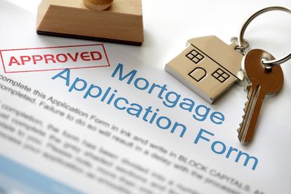 Approved mortgage loan application with house key and rubber stamp.