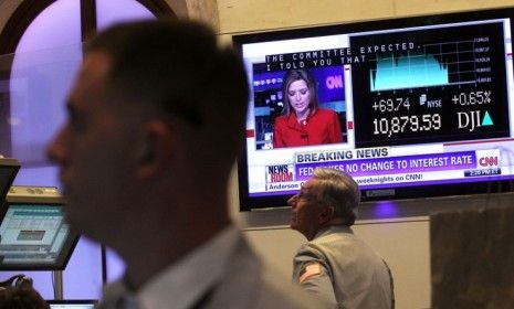 Traders on the New York Stock Exchange watch the market react to news that the Federal Reserve will keep its interest rates near zero.