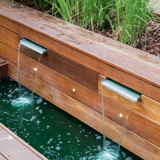 Garden water feature coming out from wooden raised beds
