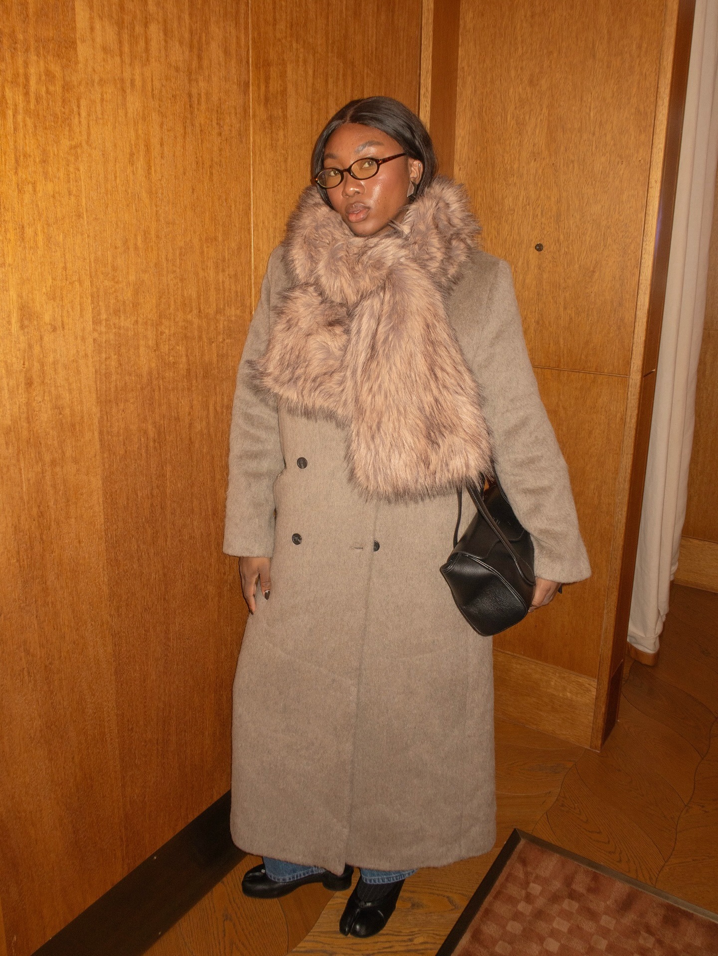 A woman wearing an oversized coat and scarf in London with shiny, dark chestnut brown hair