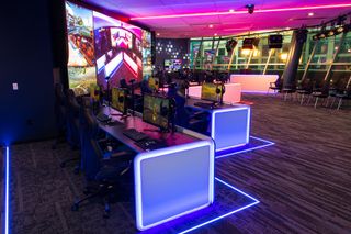 An esports venue a lit in neon lights with gamers POV displayed on an LED screen thanks to Marshall cameras.