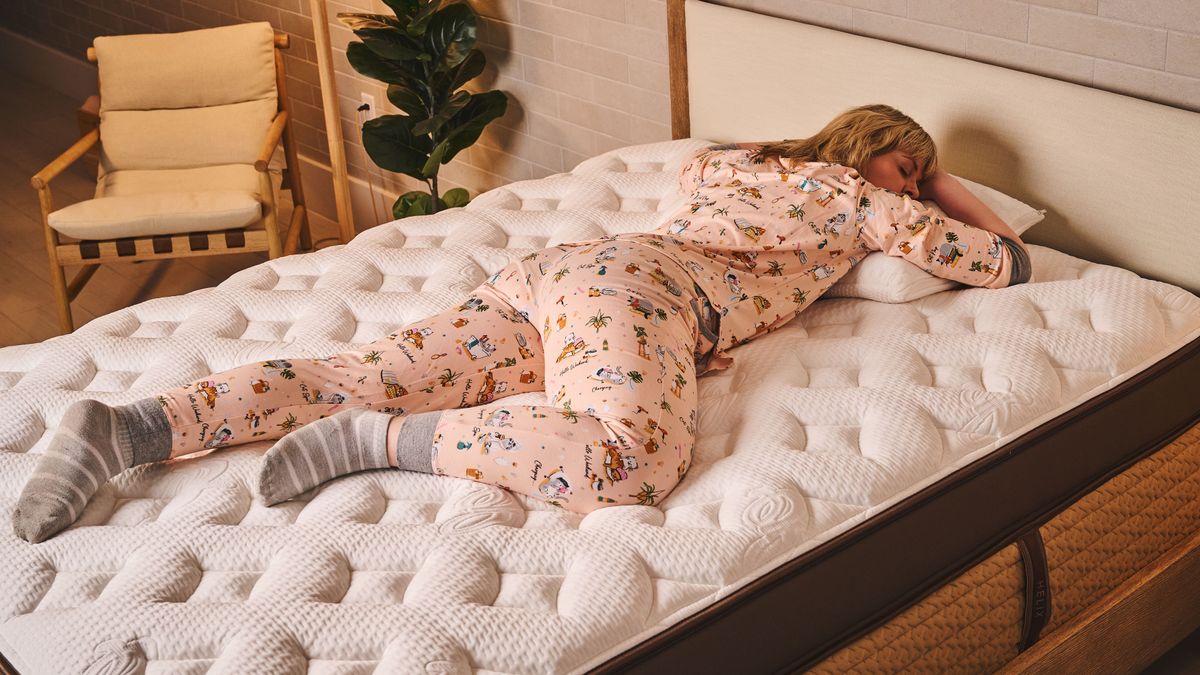 A Tom&#039;s Guide sleep tester clad in cat pajamas laying prone on the Helix Midnight Elite Mattress