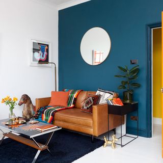 living room with navy blue feature wall and round mirror