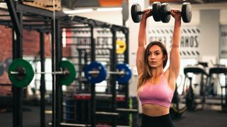Woman doing dumbbell thrusters in the gym