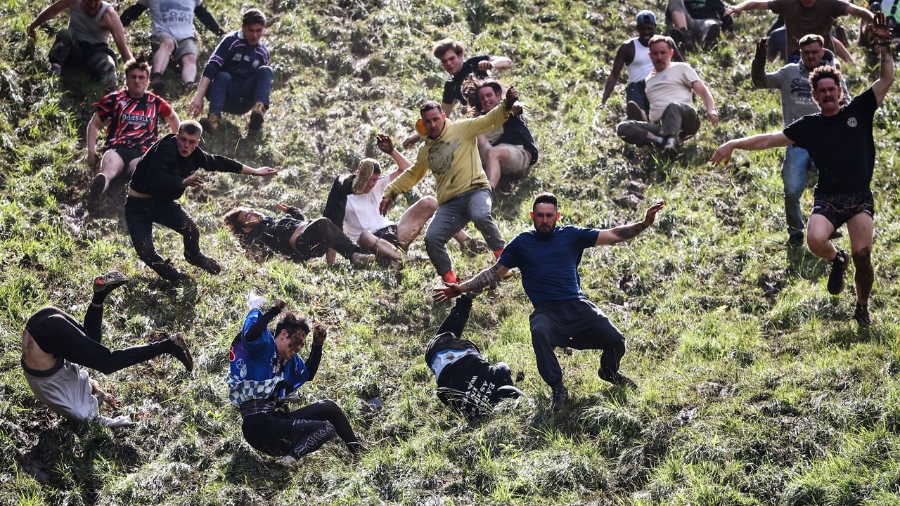 Competitors come tumbling down the hill in pursuit of a round Double Gloucester cheese during the annual Cooper&#039;s Hill cheese rolling competition