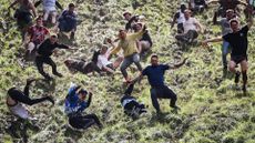 Competitors come tumbling down the hill in pursuit of a round Double Gloucester cheese during the annual Cooper's Hill cheese rolling competition