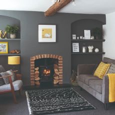 A dark grey-painted living room with a wood burning stove and a patterned black and white rug in front of it