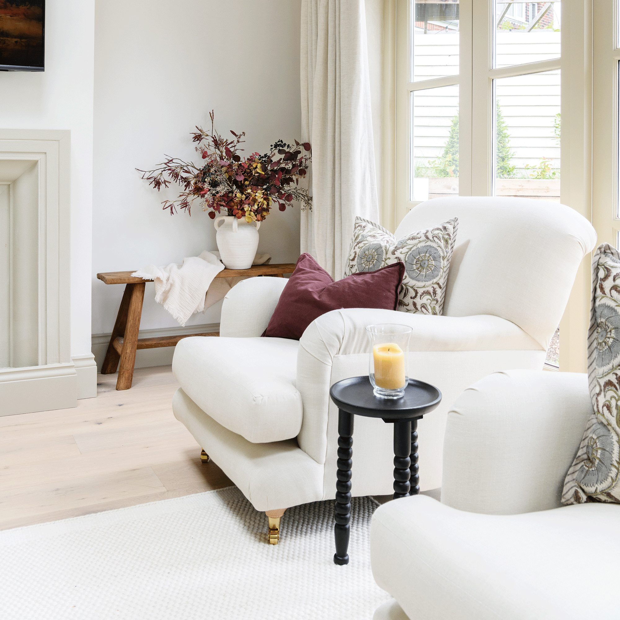 a living area with a large white armchair with cushions beside a set of patio doors