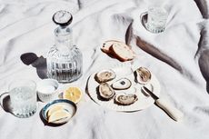 an oyster serving plate with oysters, bread and lemon