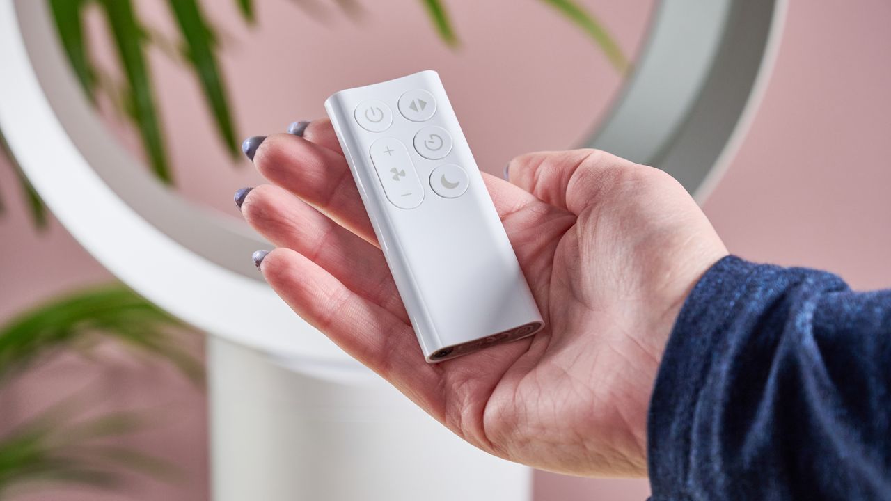 A woman's hand is holding the Dyson Cool CF1 remote.