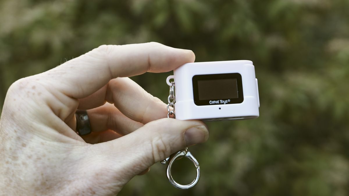 Miniature pink keychain camera, the 'Photo Creator Mini Digital Camera series 3', in user's hand, its rear screen