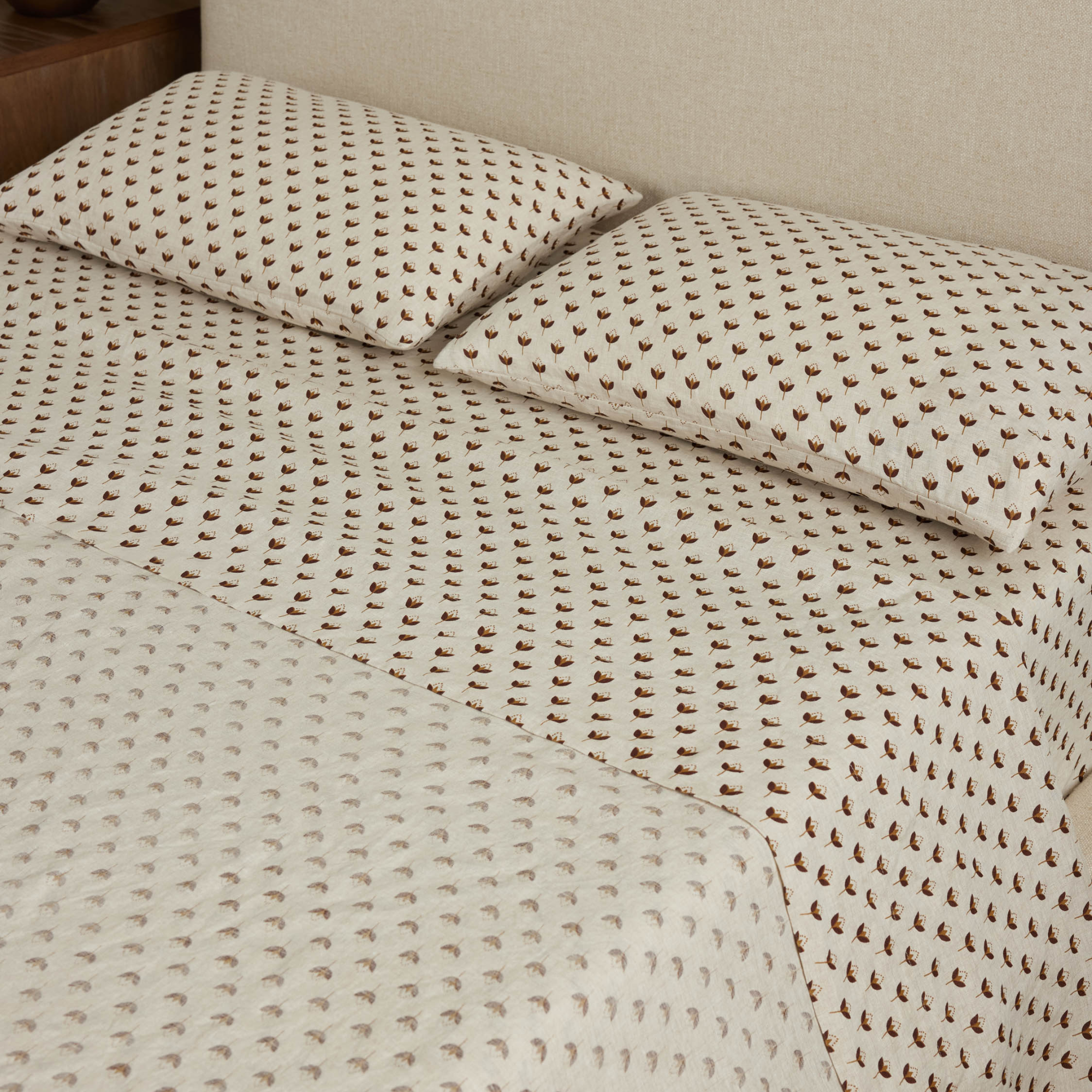 a bed with floral sheets and two pillows in matching pillowcases