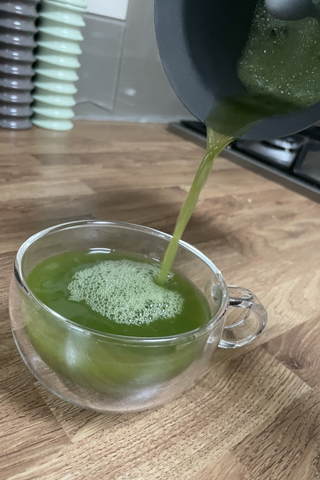 valeza pouring her matcha green tea into a glass teacup