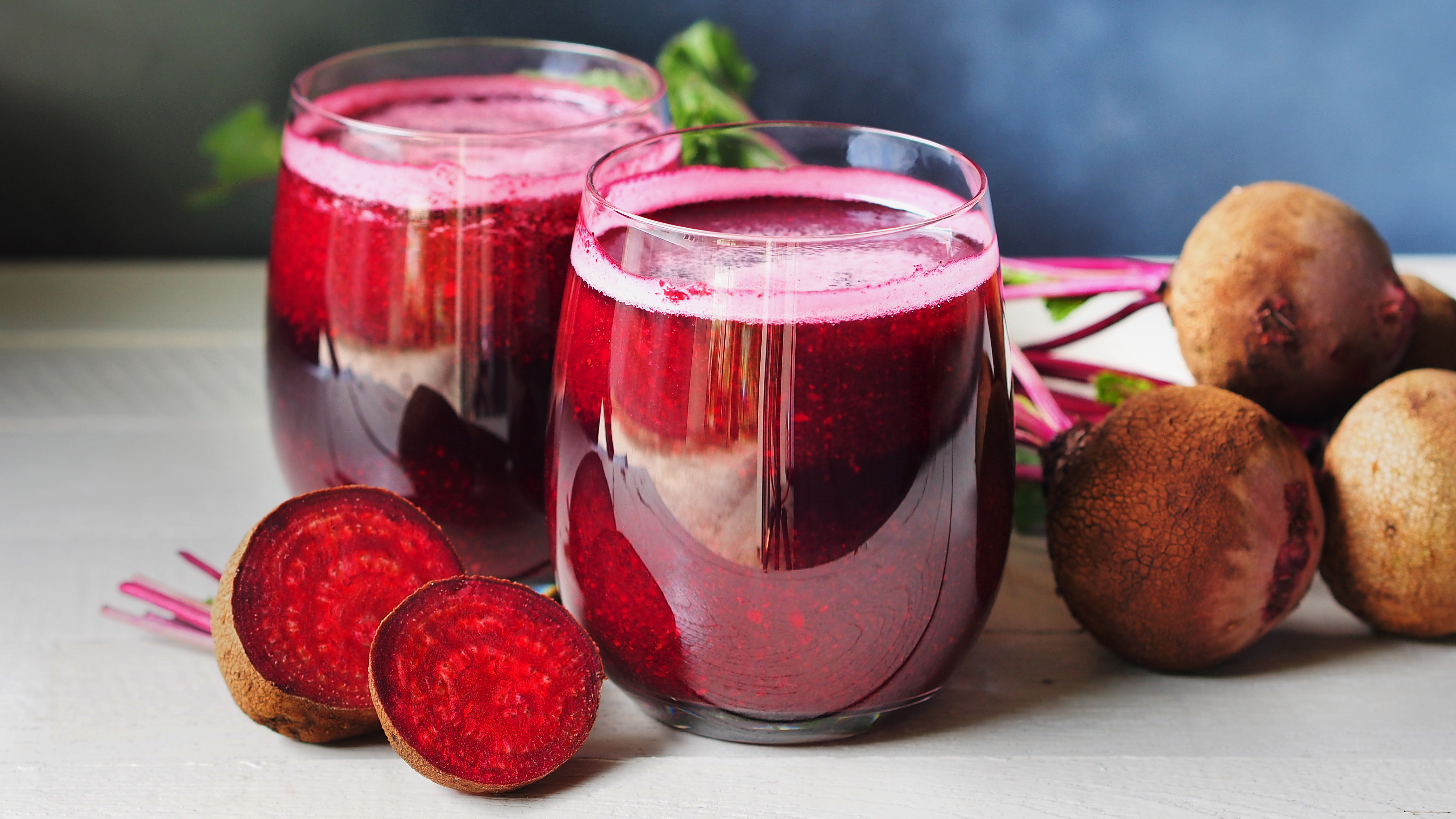 Beetroot juice in two glasses next to beets