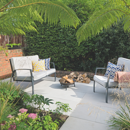 A patio area with grey garden furniture and a small fire pit.