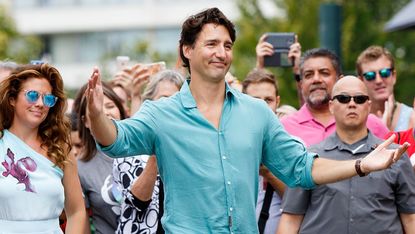 Justin Trudeau walks with arms open wide as if going in for a hug.