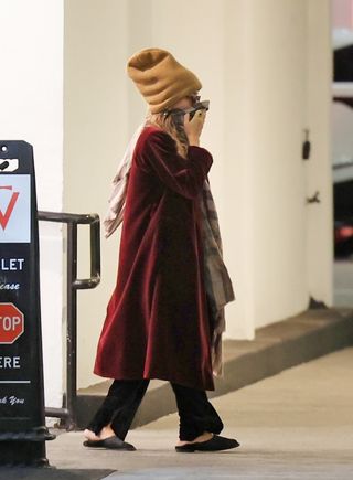 Mary-Kate Olsen wearing a tan beanie, red coat, black pants, and mules in Los Angeles.e