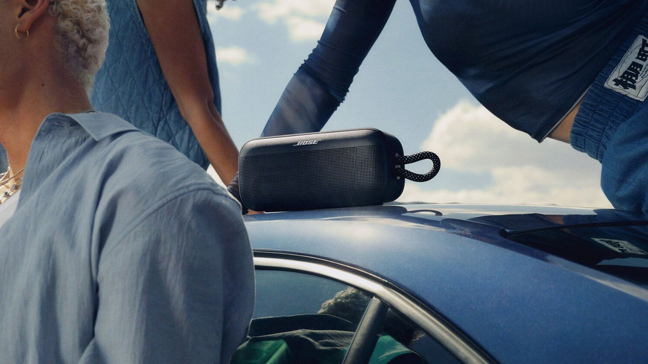 Bose SoundLink Plus Portable speaker in black on top of a blue car with people stood around it