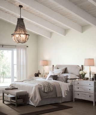 white bedroom with sloped wooden ceilings and neutral decor