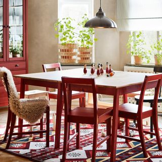 dining room with a red/wooden dining table, large windows, and a colourful rug