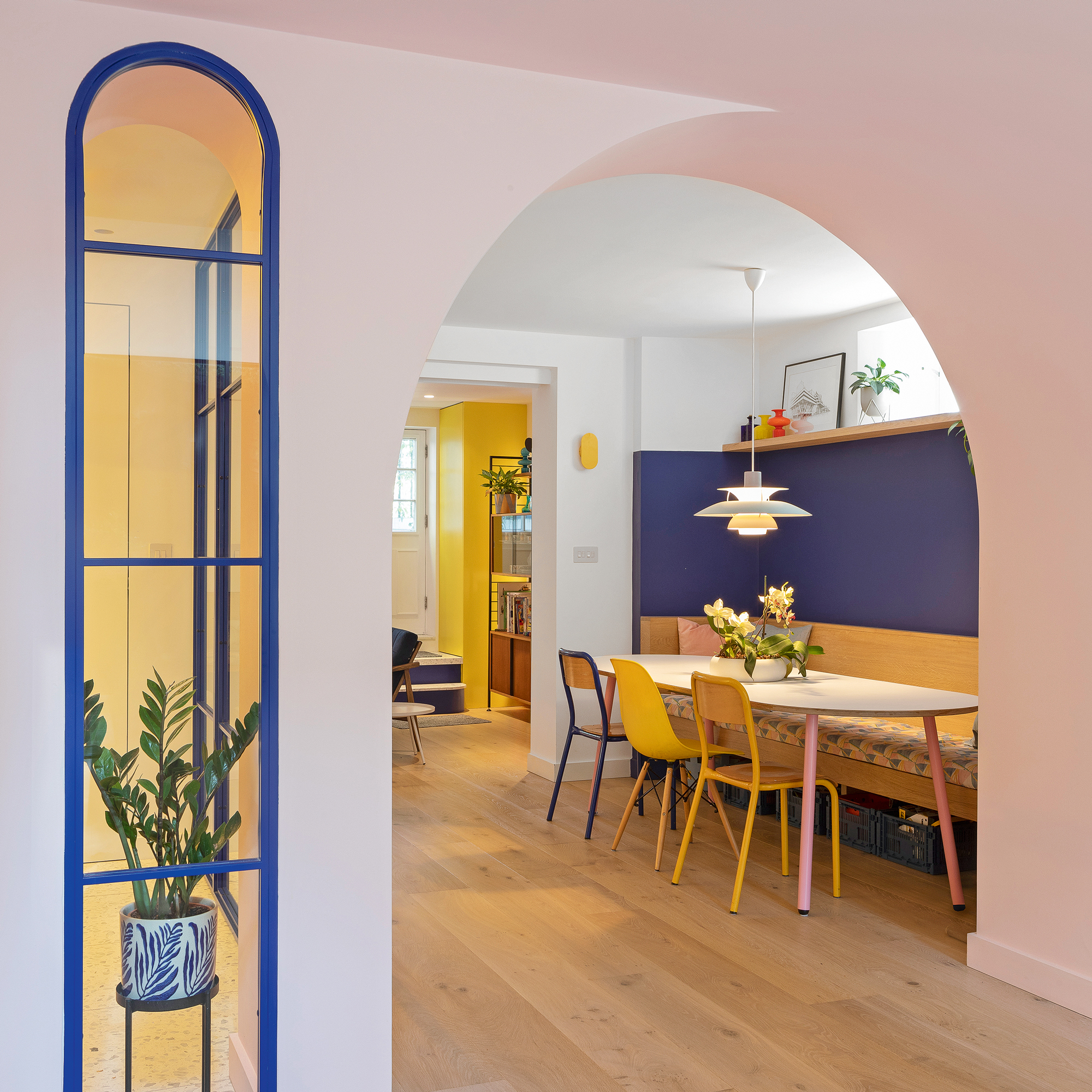 open plan kitchen diner with banquette seating and pink and purple walls
