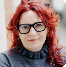 a woman with bright red hair wearing black glasses