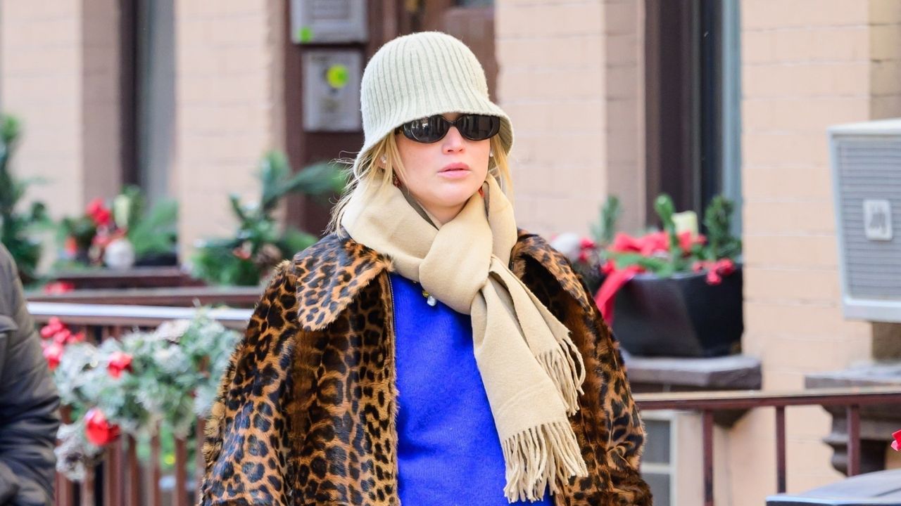 Jennifer Lawrence walking in New York City wearing a leopard print coat and cobalt sweater